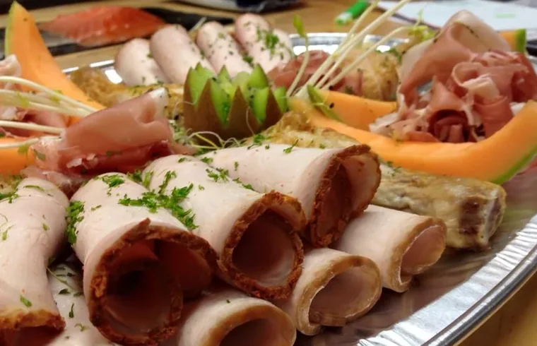 Schotel met opgerolde ham, gedroogde ham en meloen